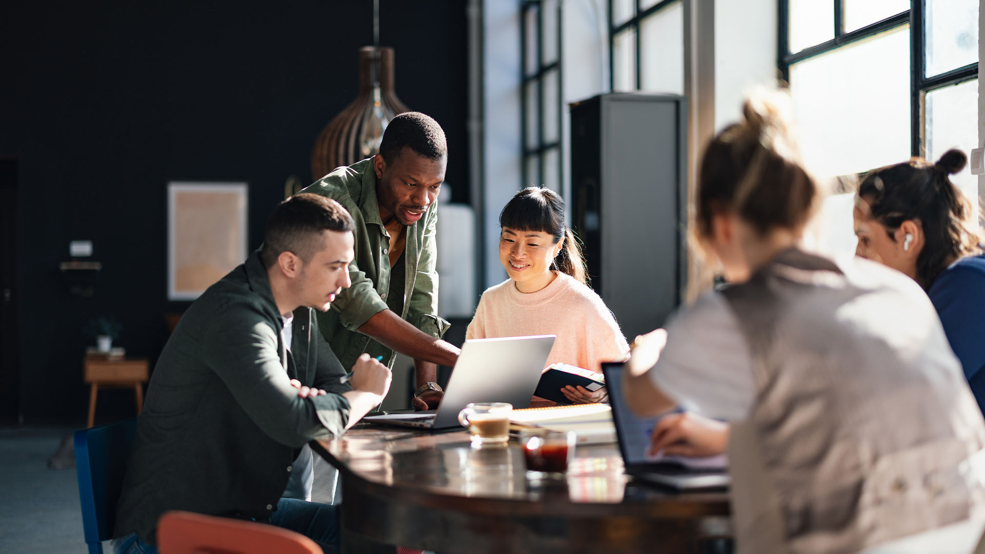 About us – collaboration Group of people working together around a laptop