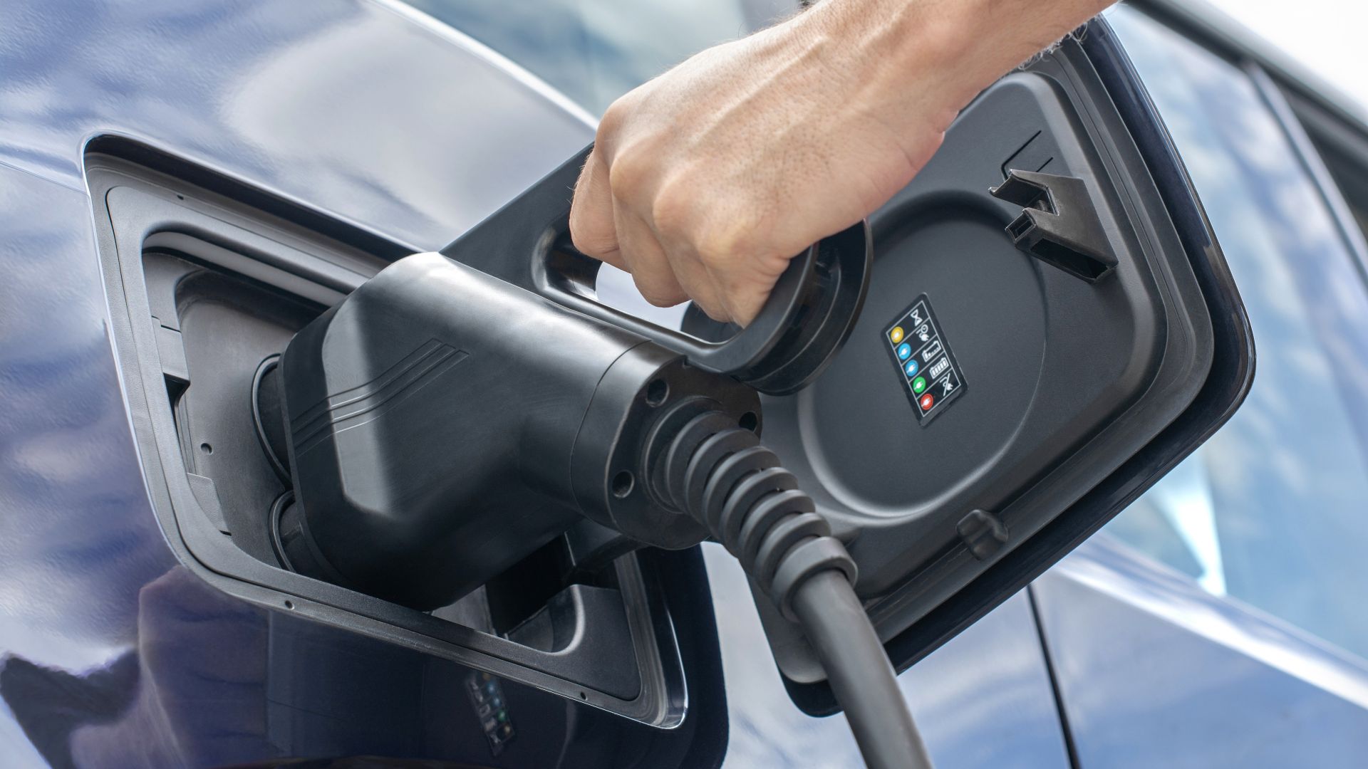 Charging gun held by an EV user and plugged into the charging port of the electric vehicle