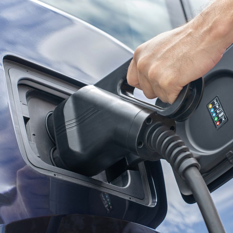 EV Charging Infrastructure – More to Explore Charging gun held by an EV user and plugged into the charging port of the electric vehicle